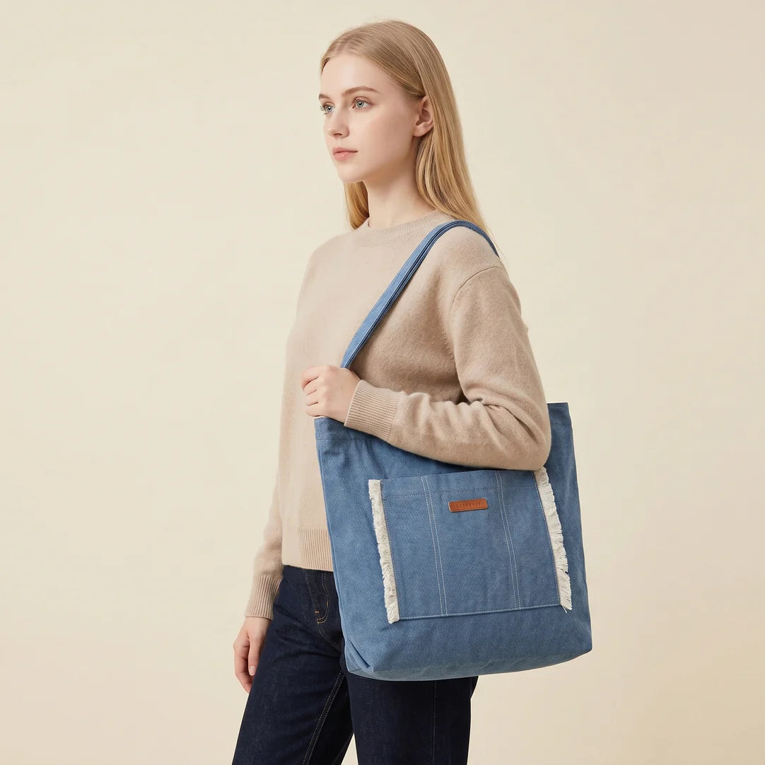 Sac à main en jean bleu en toile avec bordure blanche effilochée et petite pièce en cuir marron sur la poche avant